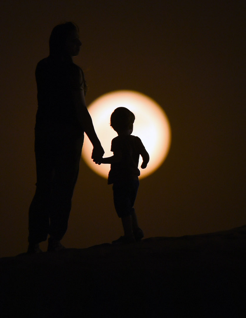 Las siluetas de una madre, su hijo y la superluna en el desierto de Dubai (Emiratos Árabes Unidos). Imagen: Tom Dulat / Getty